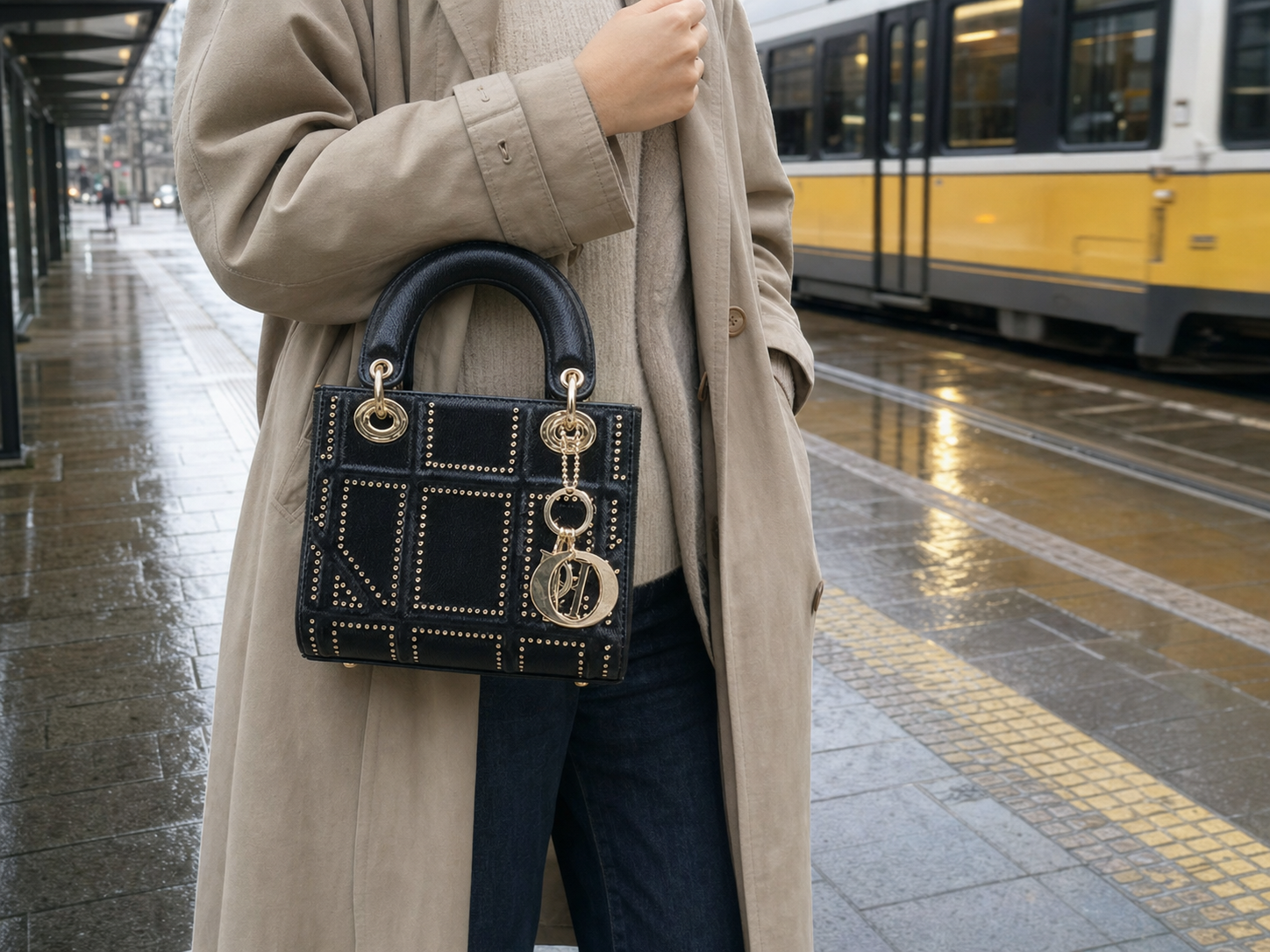 Traveller carrying the Ring Idea black studded structured bag beside a yellow tram after rain